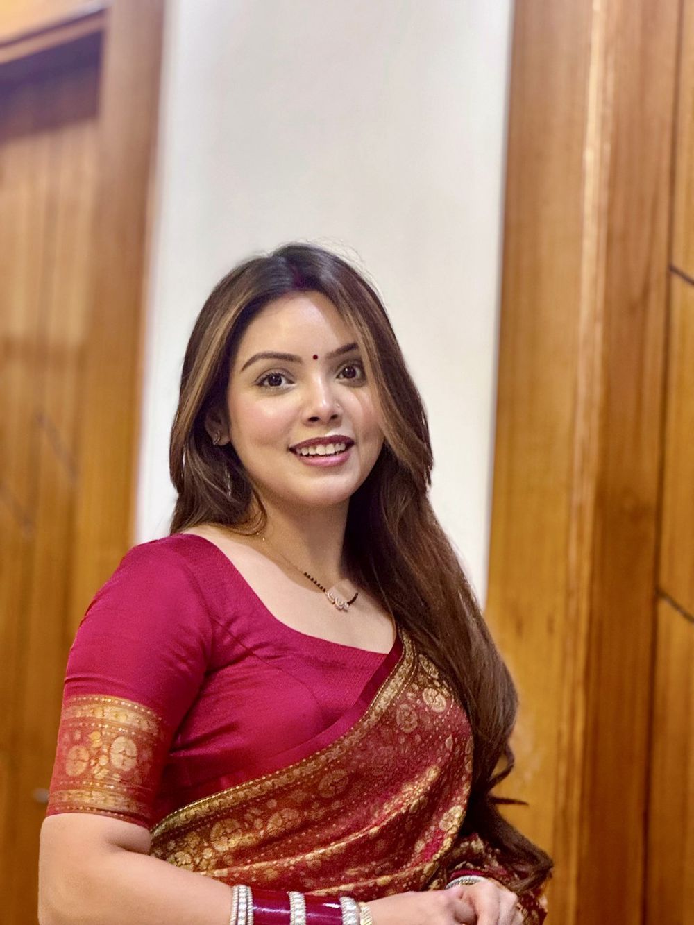 Sakshi in a red silk saree, smiling