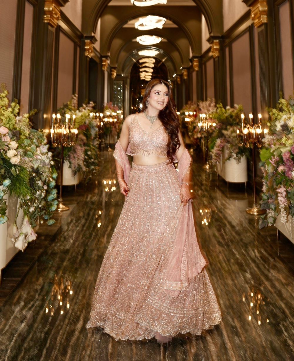 Sakshi in a blush lehenga in a candlelit corridor